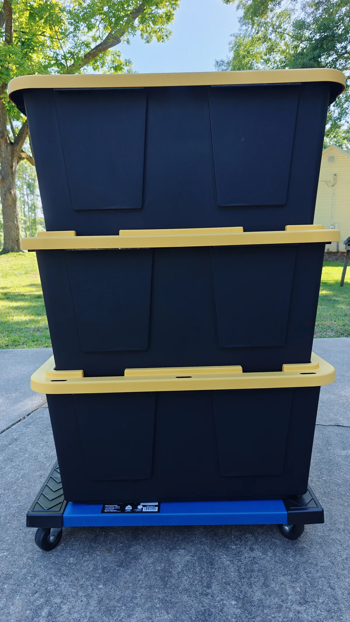 Stacked black and yellow moving totes on a dolly